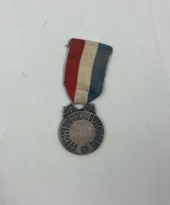 un gros plan d'une médaille posée sur une surface blanche, accompagnée d'un ruban rouge, blanc et bleu