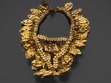 a gold necklace with leaves on a black background