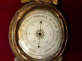 une horloge dorée accrochée à un mur rouge, sur laquelle est représenté un oiseau