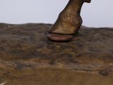 a bronze statue of a dog sitting on top of a wooden block