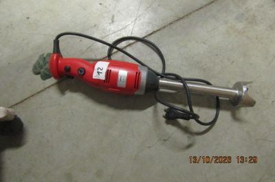 a red drill on the floor next to a black and white dog