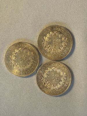 trois pièces d'or posées sur une surface blanche