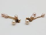 a pair of pearl and gold earrings on a white surface