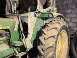 a green tractor that is parked in a barn