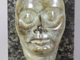 an image of a sculpture of a face on a marble block