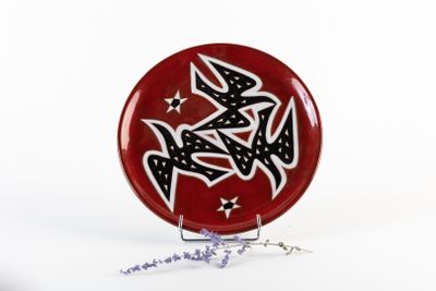 une assiette rouge ornée de motifs noirs et blancs