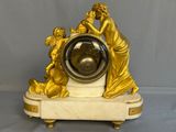 a gold clock that is sitting on a marble base
