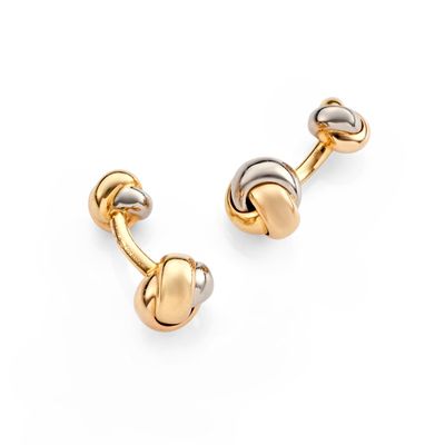 a pair of gold and silver cufflinks on a white background