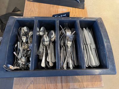 les cuillères, les fourchettes et les cuillères se trouvent dans un plateau posé sur une table