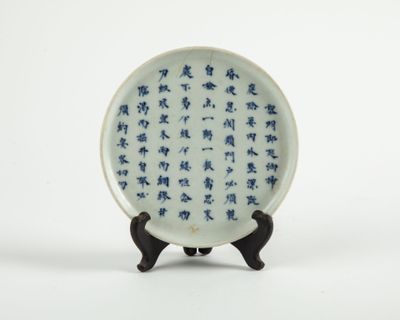une assiette décorée de motifs bleus et blancs, posée sur un socle
