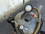 a tank with a gauge and a hose on the side of the road