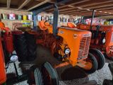 several orange tractors are lined up in a row in a garage