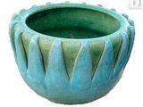un vase vert posé sur une surface blanche