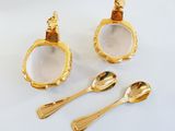 two gold spoons, a spoon and a spoon rest on a white surface