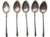 six spoons are lined up in a row on a white surface