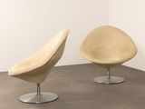 two chairs in a room with a white wall and a brown floor