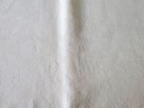 une serviette blanche posée sur une table en bois, à côté d'un couteau et d'une fourchette