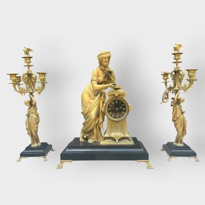 a statue of a woman holding a clock next to three candelabs