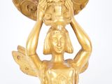 a gold statue of a woman holding a bowl on her head