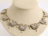 Collier doré orné de breloques en forme de cœur et de perles, présenté sur un mannequin