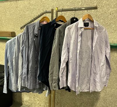 several shirts hanging on a clothes rack in a clothing store