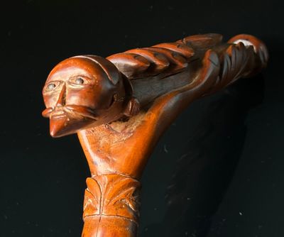 Canne en bois flammé, le pommeau sculpté d'une main tenant u…