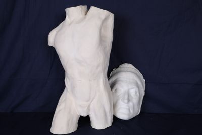une sculpture blanche représentant un torse et une tête, posée sur une table