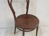 a small wooden chair with a bent back and a wooden seat