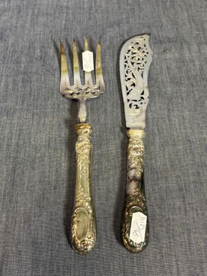 une paire de fourchettes et un couteau en métal argenté, posés sur un tissu gris