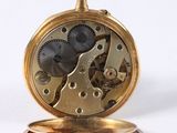 a gold pocket watch with gears on it on a white surface