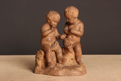 une petite statue représentant deux enfants assis sur un rocher