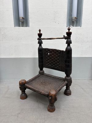une chaise en bois avec une assise tressée, placée devant un mur blanc