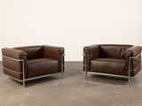 two brown leather chairs sitting next to each other in a room