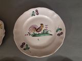 a plate with a rooster painted on it next to a bowl with cherries on it