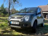 une petite voiture noire garée dans l'herbe devant une maison