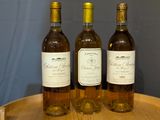 three bottles of wine sitting on top of a wooden barrel