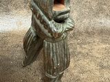 une statue représentant un homme portant un chapeau et un sac
