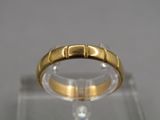 un gros plan d'une bague en or posée sur une surface transparente
