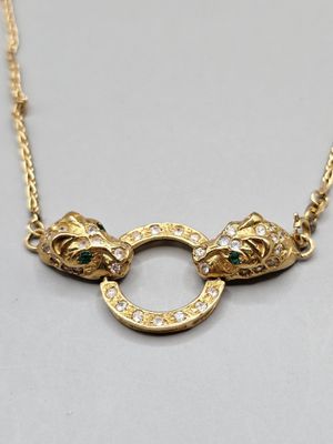a close up of a gold necklace with two cats on it