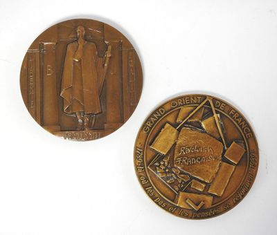 deux médailles de bronze représentant un homme et une femme, posées sur un fond blanc