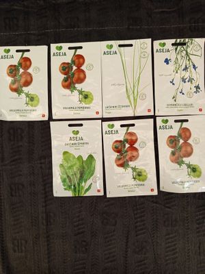 six packets of tomato seeds on a black couch