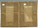 pair of old books with brown paper covers on them sitting on a white surface