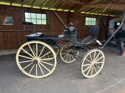 un cheval et une calèche dans une grange, avec un homme debout à côté