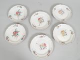six plates with floral designs are arranged on a white surface