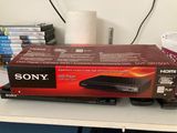 un lecteur DVD Sony posé sur un bureau, à côté d'une pile de DVD