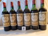 six bouteilles de vin rouge sont alignées sur une table