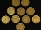 six gold coins are arranged in a triangle on a black surface