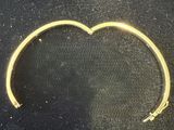 gold bracelet with a heart shaped design on it on a black surface