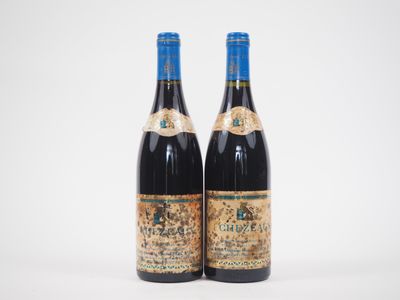 two bottles of red wine sitting next to each other on a white surface