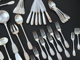 a lot of silver spoons and forks laid out on a table
